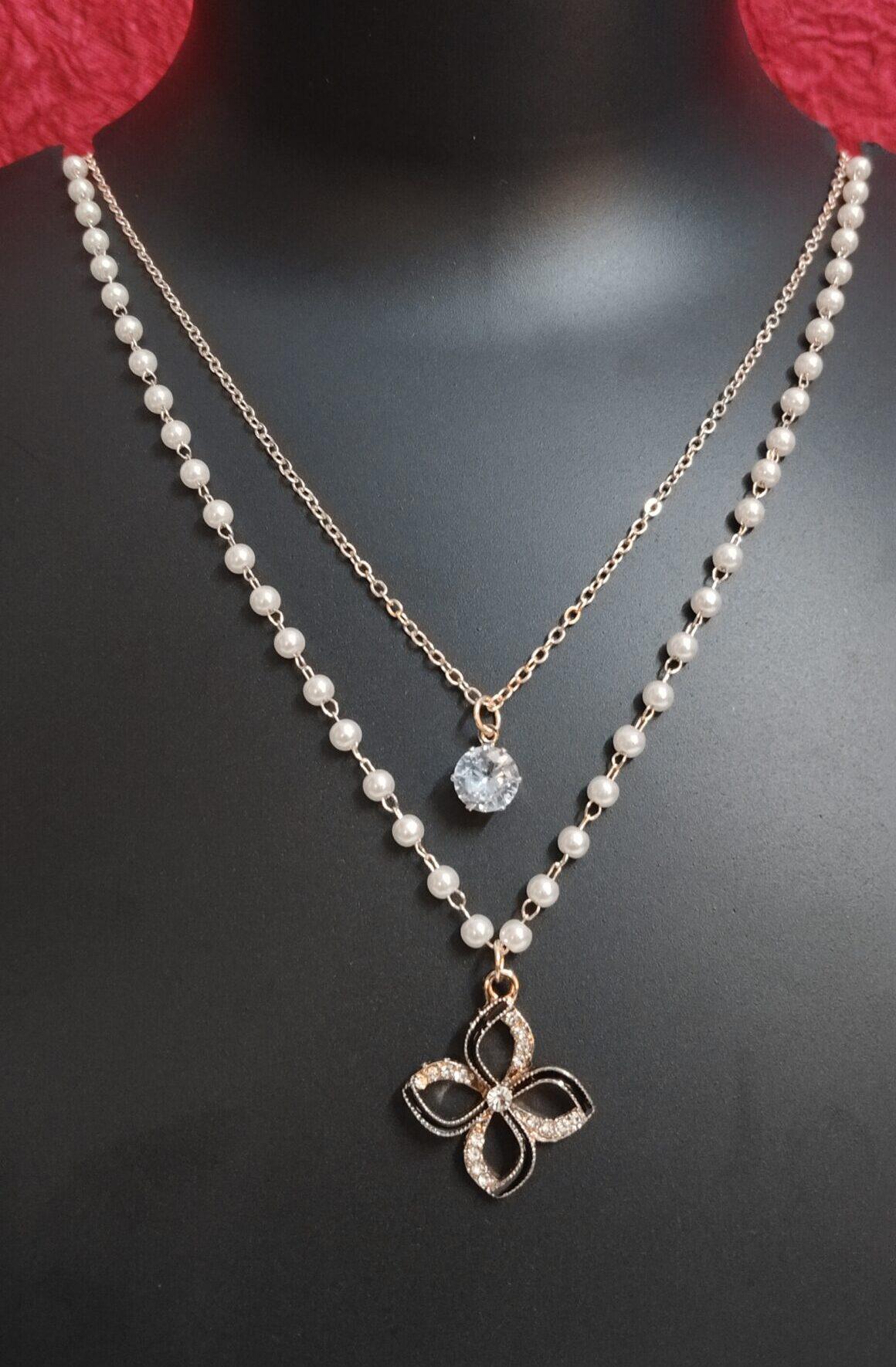 Double-layered gold-tone necklace with white beads and floral charm