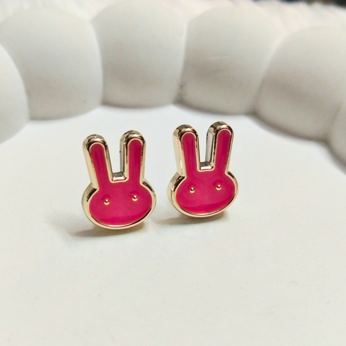 Pink bunny face stud earrings with gold outline on white background