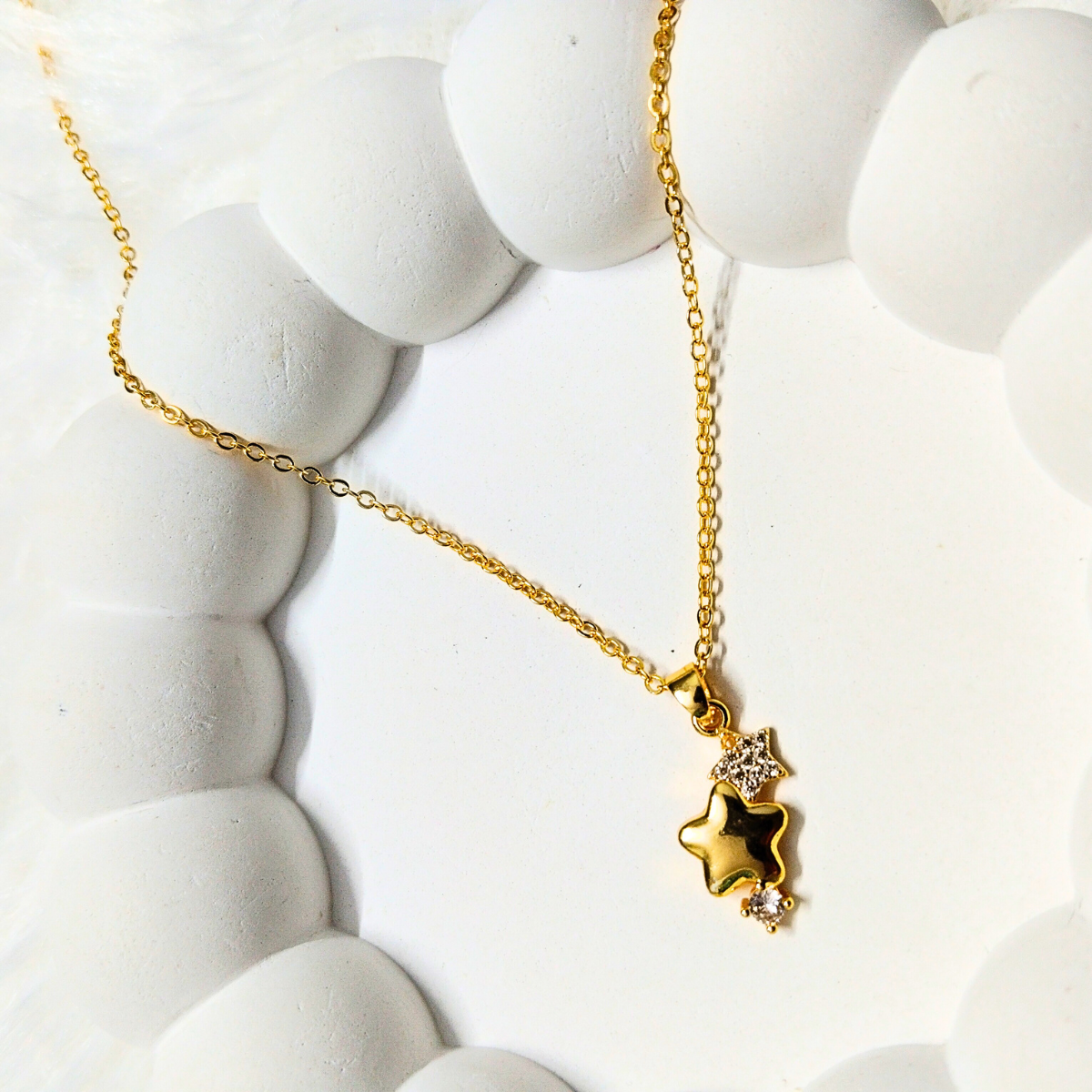 Gold star pendant necklace with triple-star charm and crystal embellishments on a delicate chain
