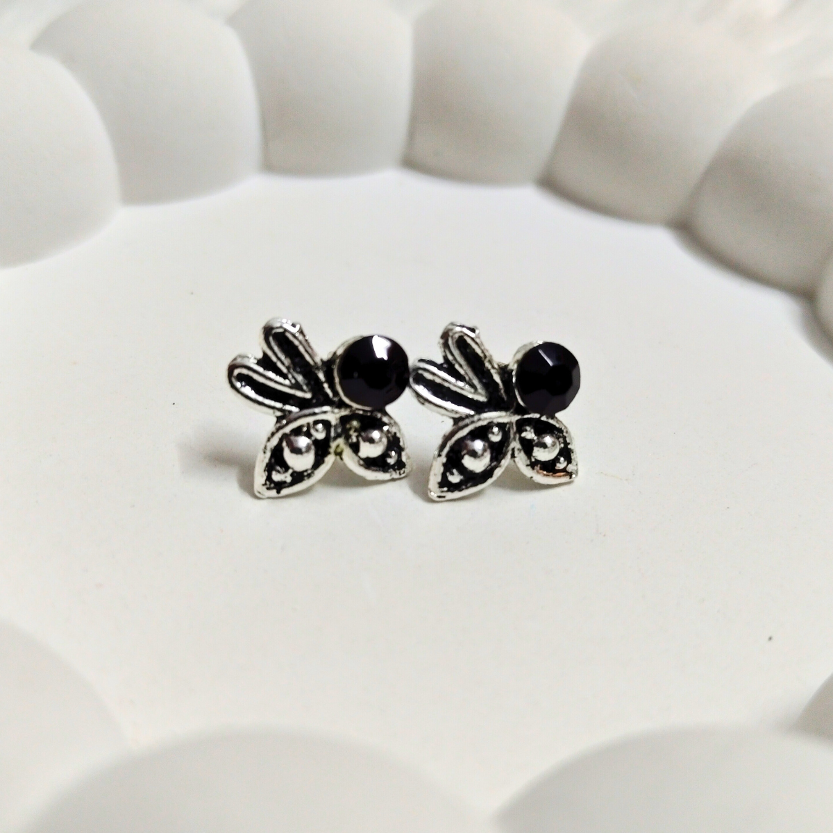 Silver stud earrings with black center stone and leaf-inspired design on white background