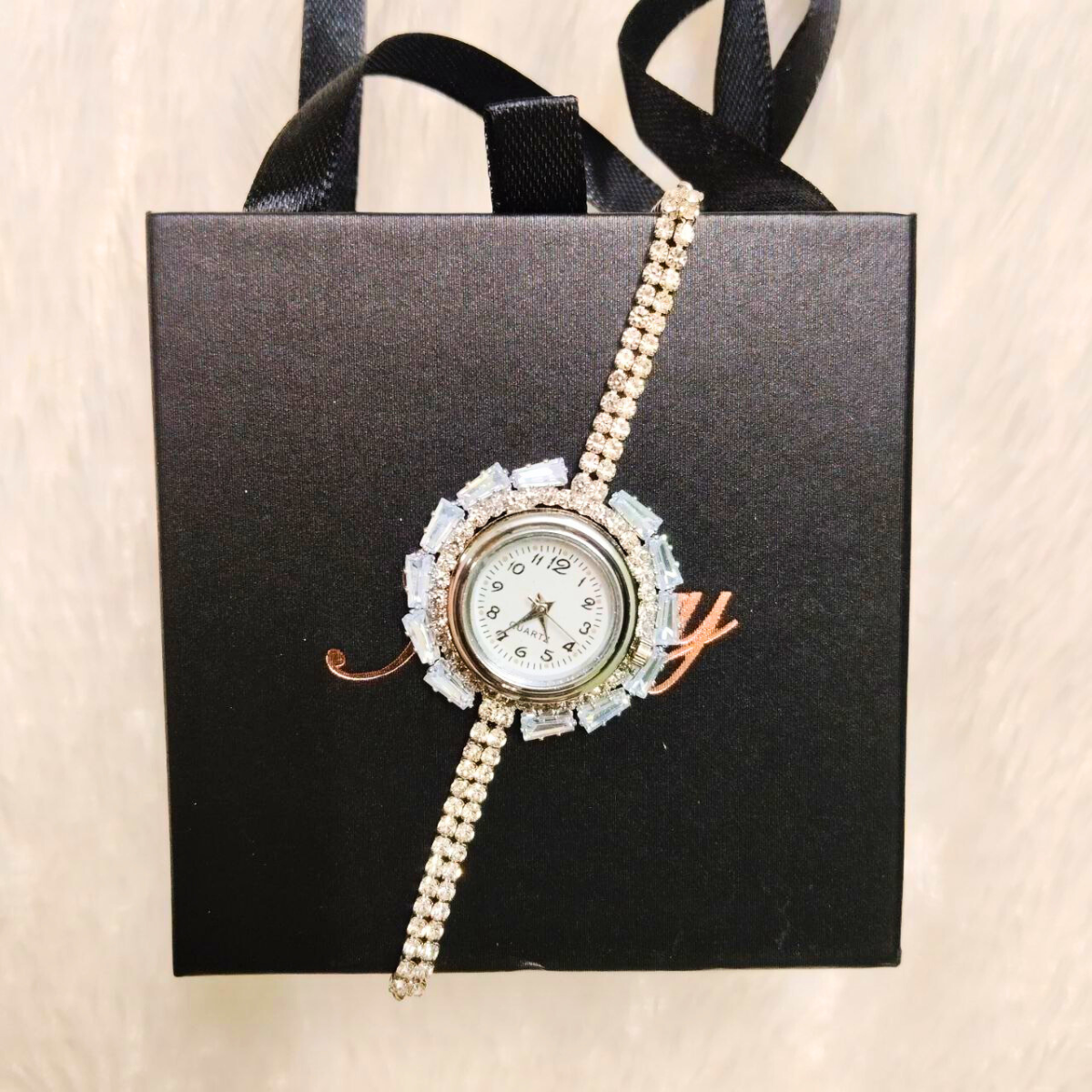 Crystal-embellished silver ladies wristwatch with round white dial on a black gift box