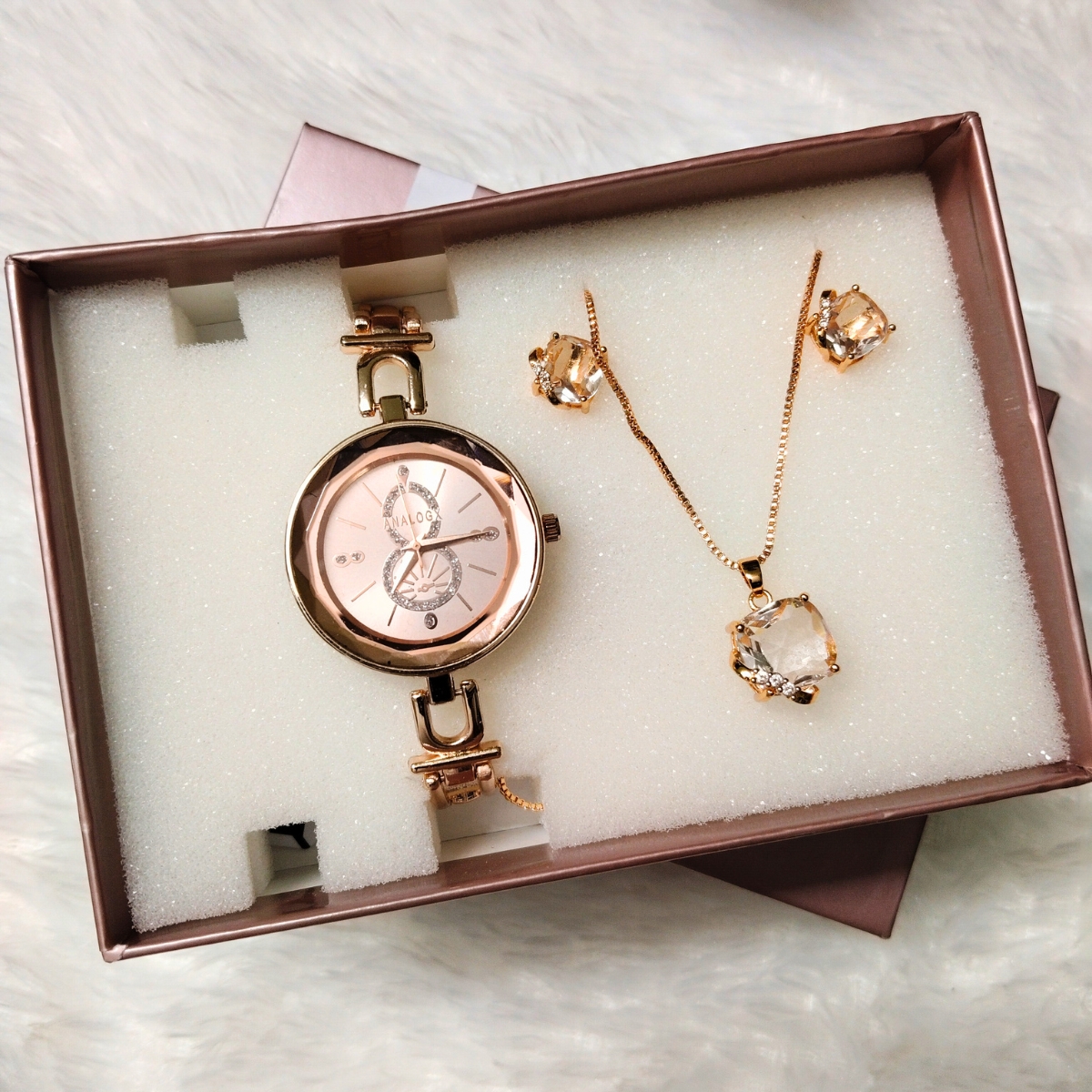 Rose gold women’s analog watch with crystal necklace and earrings combo gift set in foam packaging.
