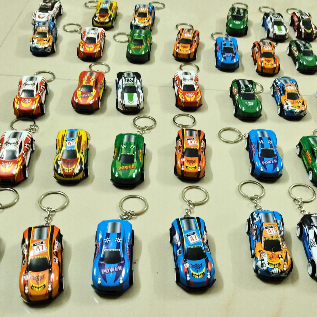 Assorted mini Pushback Racing Car Keychains arranged in rows with colorful racing designs
