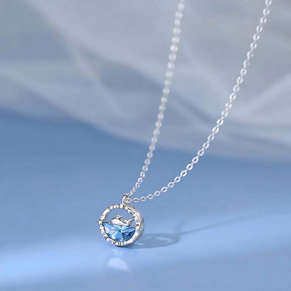 Silver dolphin necklace with round ocean blue crystal pendant on a delicate chain